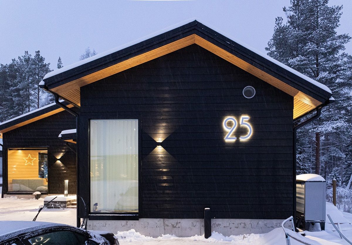 Wall lights reflecting on the light-coloured eaves cladding enhance the appearance of a dark house